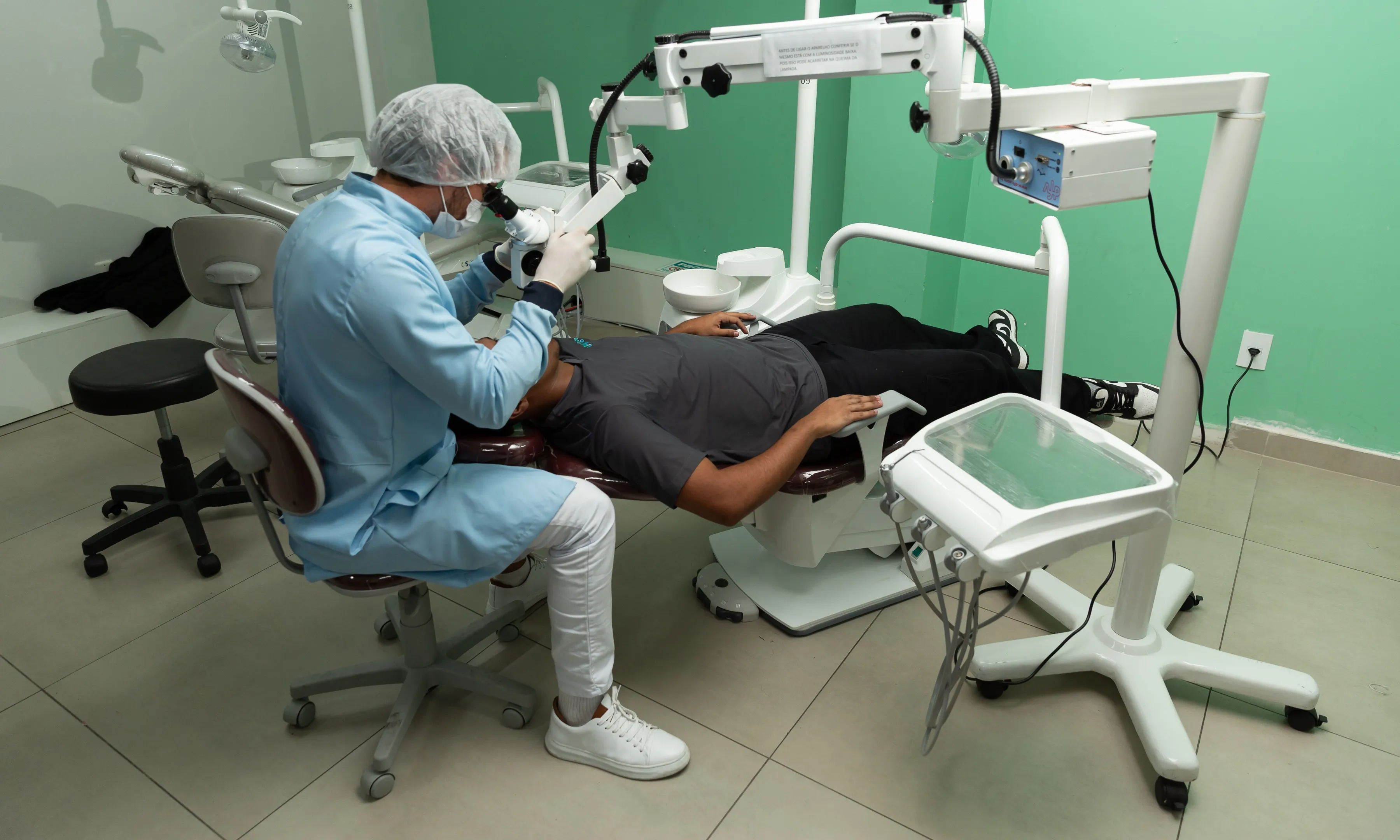 Dentista atendendo com microscópio operatório na clínica da Odonto & Med